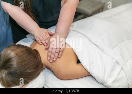 Gros plan d'un message thérapeute féminin donnant à une femme un massage des épaules dans un spa local Banque D'Images