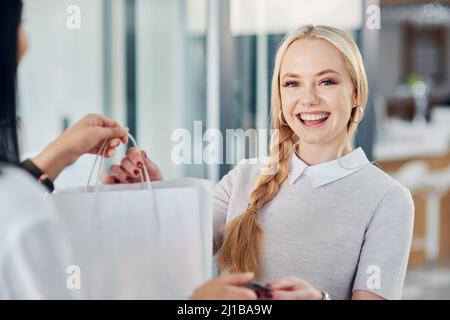 Je suis toujours heureux quand j'ai obtenu une bonne affaire. Coupe courte d'une jeune femme qui fait un achat dans un magasin de vêtements. Banque D'Images