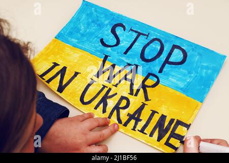 Petite fille ukrainienne dessine une image avec le drapeau de l'Ukraine et le texte ARRÊTER LA GUERRE EN UKRAINE. 2022 invasion russe de l'Ukraine. Banque D'Images