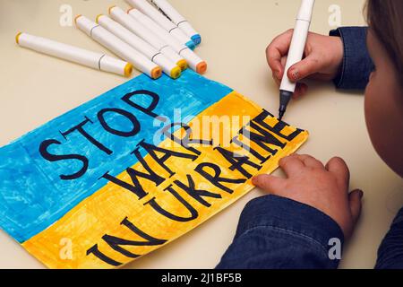 Petite fille ukrainienne dessine une image avec le drapeau de l'Ukraine et le texte ARRÊTER LA GUERRE EN UKRAINE. 2022 invasion russe de l'Ukraine. Banque D'Images