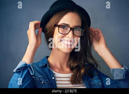 Continuez à sourire. Portrait d'une jeune femme originale souriant sur fond gris en studio. Banque D'Images