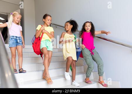 Une longueur complète de filles d'école primaire multiraciale qui se déplacent vers le bas dans la construction de l'école Banque D'Images