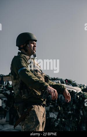 Le guerrier ukrainien de la défense territoriale se tient sur un point de contrôle dans une armure de corps avec arme automatique. Concept d'invasion militaire russe en Ukraine. La guerre en U Banque D'Images