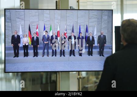 Bruxelles, Belgique. 24th mars 2022. Un homme regarde un écran montrant des dirigeants posant pour une photo de groupe lors d'une réunion de G7 dirigeants au siège de l'OTAN à Bruxelles, Belgique, le 24 mars 2022. Credit: Zheng Huansong/Xinhua/Alay Live News Banque D'Images