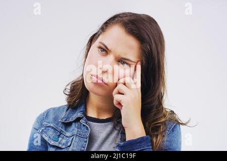 Votre tête peut être votre pire ennemi. Photo studio d'une jeune femme qui a l'air réfléchie sur un fond gris. Banque D'Images