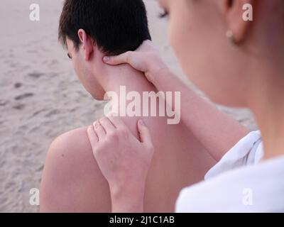 Un jeune chiromassothérapeute offrant des massages de l'épaule et du cou à un jeune homme sur une plage de Valence. Banque D'Images