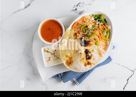 biryani de légumes avec raita et sauce dans un plat isolé sur le côté de la serviette vue sur fond gris célèbre cuisine indienne et pakistanaise Banque D'Images