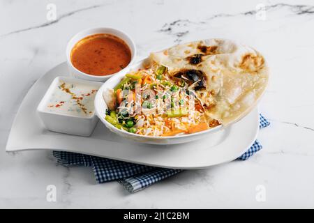 biryani de légumes avec raita et sauce dans un plat isolé sur le côté de la serviette vue sur fond gris célèbre cuisine indienne et pakistanaise Banque D'Images