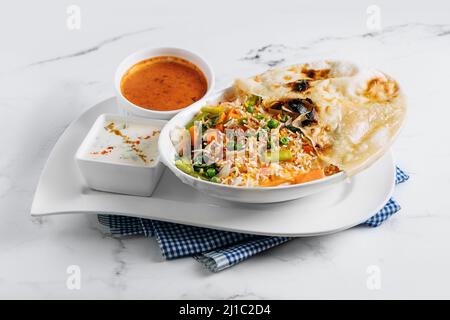 biryani de légumes avec raita et sauce dans un plat isolé sur le côté de la serviette vue sur fond gris célèbre cuisine indienne et pakistanaise Banque D'Images