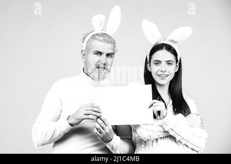 Le couple de Pâques tient un tableau blanc vierge pour votre texte. Portrait du couple de Pâques heureux. Banque D'Images