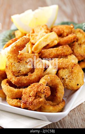 Rondelles de calmar frites panées avec du citron sur une assiette Banque D'Images