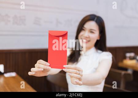 Belle jeune femme asiatique en robe blanche traditionnelle nommée cheongsam assis dans un restaurant japonais ou une cafétéria et attendant la nourriture commandée. Fille Banque D'Images