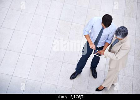 Les professionnels qui réussissent comprennent l'importance des réseaux. Portrait grand angle d'un homme et d'une femme professionnels utilisant une tablette. Banque D'Images