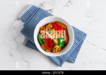 Légumes mélangés Aloo Gobhi et Shimla Mirch dans un plat isolé sur le côté de la serviette vue sur fond gris célèbre cuisine indienne et pakistanaise Banque D'Images