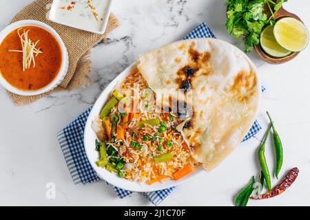 biryani de légumes avec raita et sauce dans un plat isolé sur le côté de la serviette vue sur fond gris célèbre cuisine indienne et pakistanaise Banque D'Images