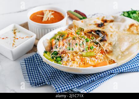 biryani de légumes avec raita et sauce dans un plat isolé sur le côté de la serviette vue sur fond gris célèbre cuisine indienne et pakistanaise Banque D'Images