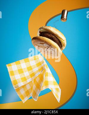 Vue sur un délicieux hamburger volant avec serviette en fond bleu et orange Banque D'Images