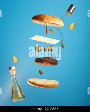 Vue sur un délicieux hamburger volant avec des ingrédients sur fond bleu Banque D'Images