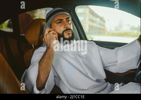 Saoudien assis dans une voiture et parlant au téléphone Banque D'Images