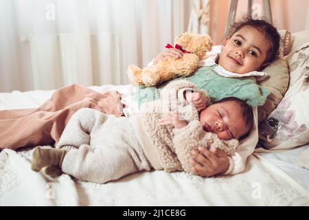 Petite fille multiethnique, sœur couchée à côté de son frère sur le lit Banque D'Images