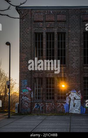 Dortmund, ALLEMAGNE - 19. Mars 2022: Sur l'ancien site industriel Phoenix Ouest le soleil levant brille à travers une vieille fenêtre d'un hall en brique Banque D'Images