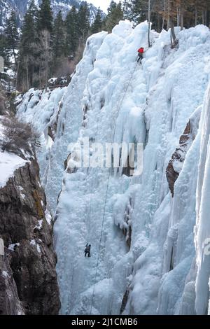 Un grimpeur à gauche monte alors qu'un autre grimpeur à droite descend un mur de glace de 160 m de haut dans le parc de glace d'Ouray, Colorado. Banque D'Images