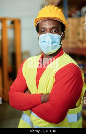 Portrait d'un travailleur africain à l'intérieur d'un entrepôt avec sécurité Masque - concentrez-vous sur les yeux de l'homme Banque D'Images