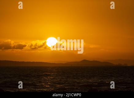 Soleil levant sur les nuages avec des collines de distance à l'horizon. Photo prise depuis Milford Beach, Auckland. Banque D'Images