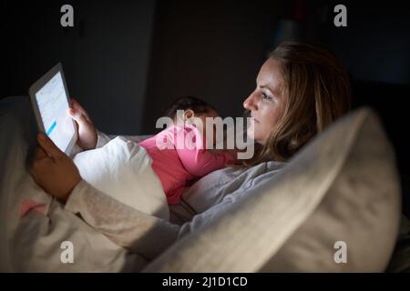 Sa façon de lier les mamans lors de la navigation. Prise de vue d'une mère à l'aide d'une tablette numérique alors que son bébé dort sur sa poitrine à la maison. Banque D'Images