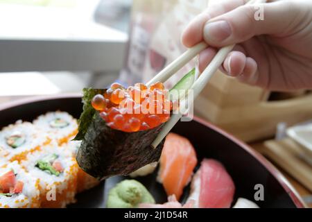 Une femme mange du gunkanmaki dans un restaurant japonais Banque D'Images