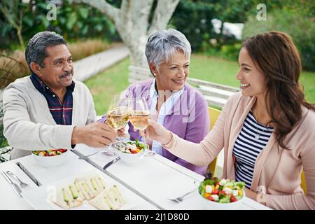 Ils l'aiment quand leur fille vient visiter. Une photo de famille qui toaster pendant son déjeuner tout en étant assis à l'extérieur. Banque D'Images