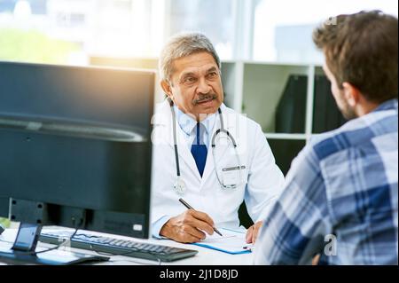 J'ai besoin que vous vous concentriez sur les éléments répertoriés par IVE. Prise de vue d'un médecin homme mature et confiant consultant un patient à l'intérieur de son bureau pendant le Banque D'Images