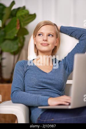 Composition de son prochain post. Photo d'une belle femme assise sur un canapé à l'aide d'un ordinateur portable. Banque D'Images