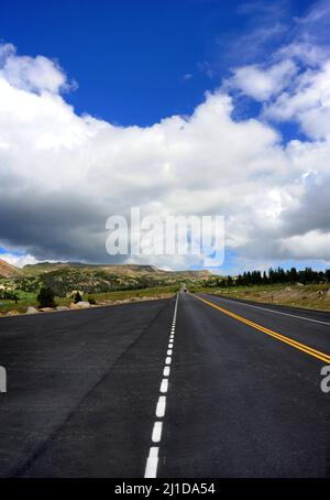 Le camion disparaît au loin lorsqu'il conduit le Beartooth Pass Scenic Byway. Les nuages survolez la montagne et envolez-vous dans un ciel bleu. Banque D'Images