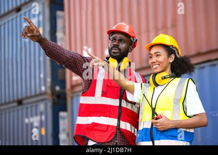 Deux travailleurs afro-américains, hommes et femmes, vérifient et contrôlent le chargement des conteneurs de fret à partir du navire de fret de fret pour l'exportation à l'importation. Banque D'Images