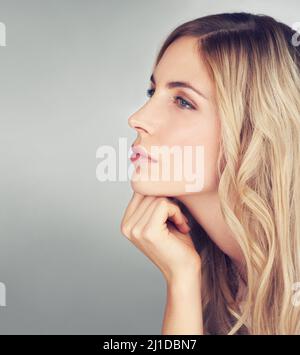 Penser au prochain meilleur soin de la peau. Vue latérale d'une jeune femme attrayante qui a l'air attentionnés dans un studio. Banque D'Images