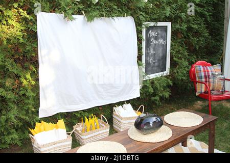 Fiche technique blanc prêt pour une soirée cinéma en plein air avec de la nourriture et des chaises Banque D'Images