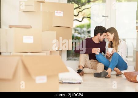 S'installer dans leur nouvelle maison. Photo d'un jeune couple affectueux prenant une pause-café tout en se déplaçant dans une nouvelle maison. Banque D'Images
