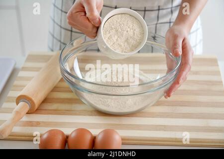 Gros plan des mains de la femme versant la farine dans le bol. Augmentation du prix du blé, de la farine et du pain. Préparation de pain maison. Crise économique. Banque D'Images