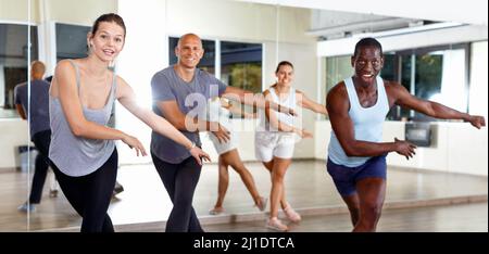 Des gens joyeux pratiquant des mouvements de sauts lindy vigoureux en classe de danse Banque D'Images