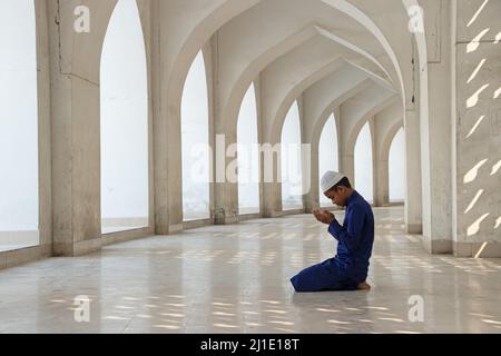 Dhaka, Dhaka, Bangladesh. 25th mars 2022. Un enfant prie à la mosquée nationale Baitul Mukarram à Dhaka, au Bangladesh. La mosquée nationale du Bangladesh, connue sous le nom de Baitul Mukarram ou la Maison Sainte en anglais, est l'une des 10 plus grandes mosquées au monde et peut accueillir jusqu'à 40 000 personnes, y compris dans l'espace ouvert extérieur. La mosquée possède plusieurs caractéristiques architecturales modernes tout en préservant les principes traditionnels de l'architecture moghole qui domine depuis un certain temps dans le sous-continent indien. (Credit image: © Joy Saha/ZUMA Press Wire) Credit: ZUMA Press, Inc./ Banque D'Images