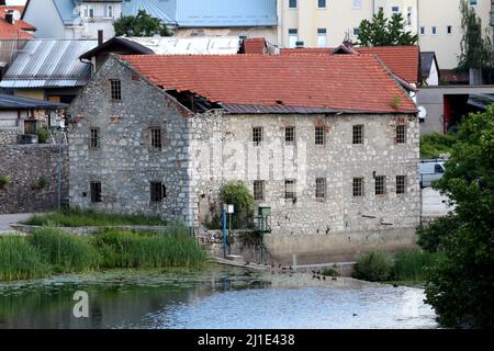 Grand bâtiment ancien abandonné avec des murs en pierre traditionnels et des fenêtres en béton sans verre recouvert de tuiles de toit rouges détruites Banque D'Images