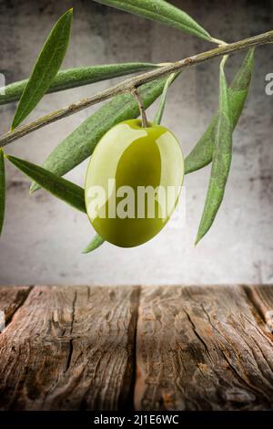 Olive verte avec brindilles et feuilles sur fond de bois Banque D'Images