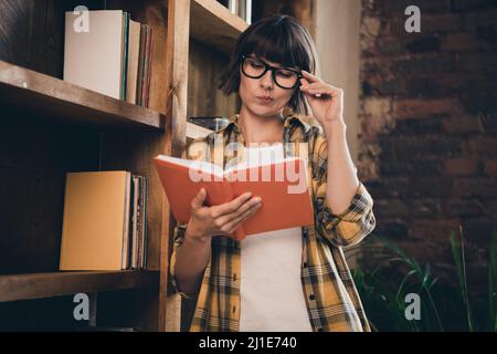 Photo de charmante grimace grimacing fille pondering livre de lecture intéressante histoire de détective à la maison à l'intérieur Banque D'Images