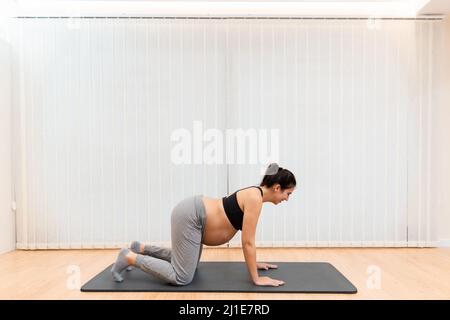 Une femme enceinte s'agenouillant sur un tapis faisant du yoga au centre de spa Banque D'Images