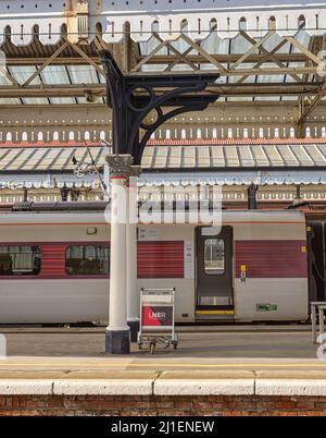 Plate-forme de la gare avec un train et une porte ouverte. Au-dessus de l'hôtel se trouve une voûte historique et un chariot se trouve à côté de certaines colonnes. Banque D'Images