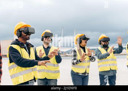 Équipe multiraciale de travailleurs industriels utilisant des micro-casques de réalité virtuelle en extérieur dans le port de terminal de fret d'expédition - Metaverse et concept logistique de fret Banque D'Images