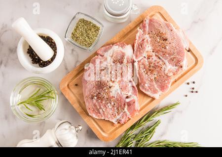 deux morceaux de porc frais sur le plan de cuisine et une table en marbre pour les steaks grillés aux épices. vue du dessus Banque D'Images