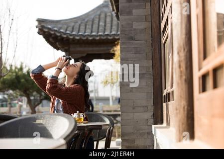 Femelle chinoise de col blanc prenant des photos et appréciant le thé de l'après-midi dans le café-terrasse - photo de stock Banque D'Images