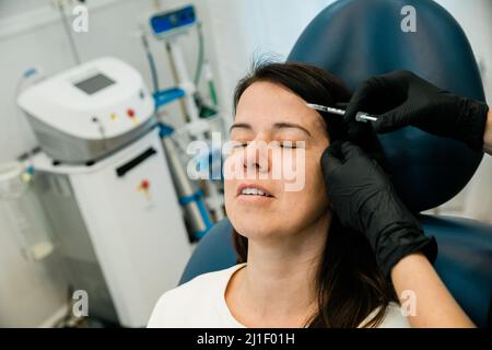 Gros plan d'une femme qui obtient la toxine botulinique ou les charges sur son front et le visage Banque D'Images